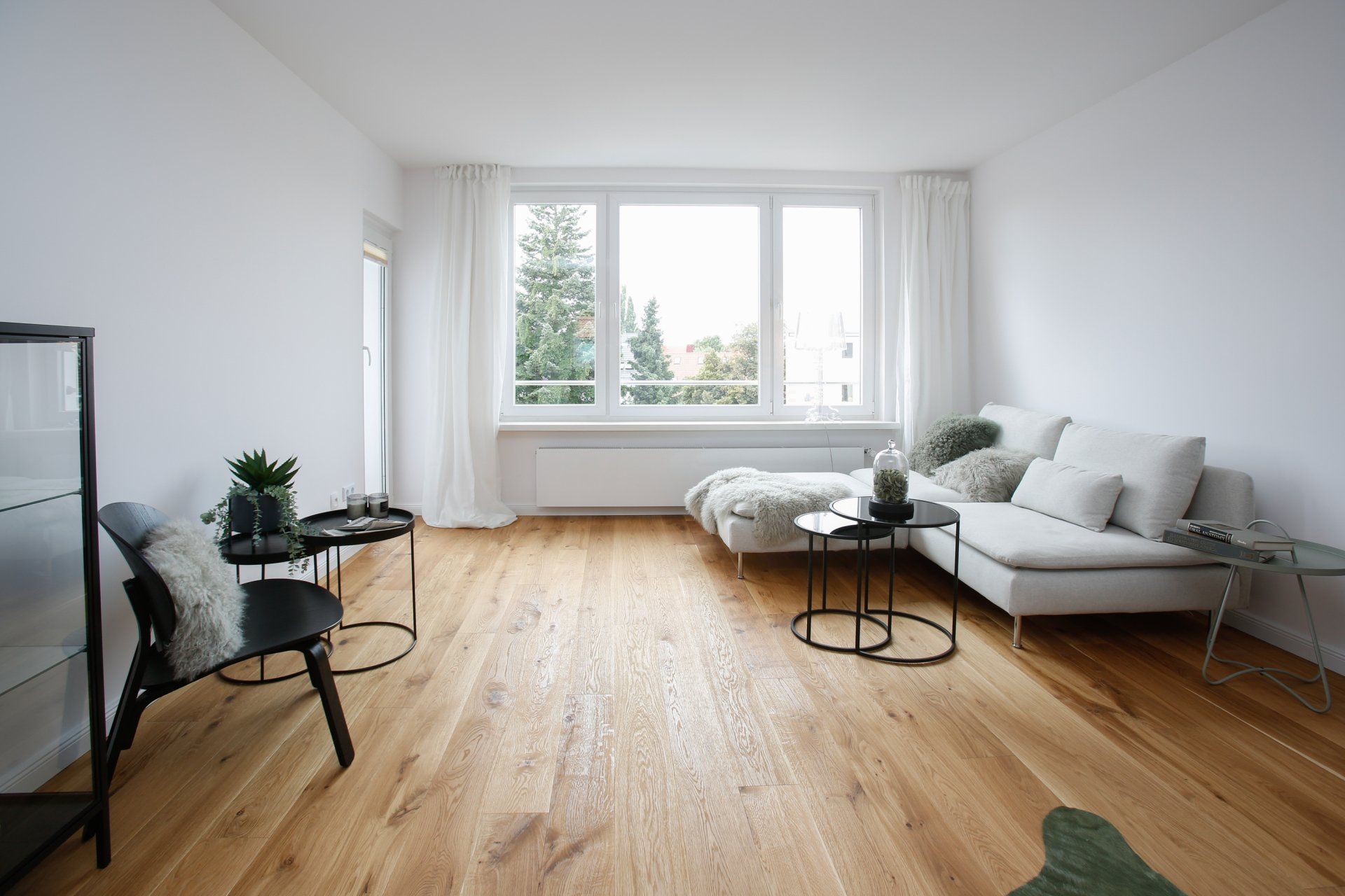 Ein Wohnzimmer mit Couch, Tisch, Stühlen und großem Fenster.