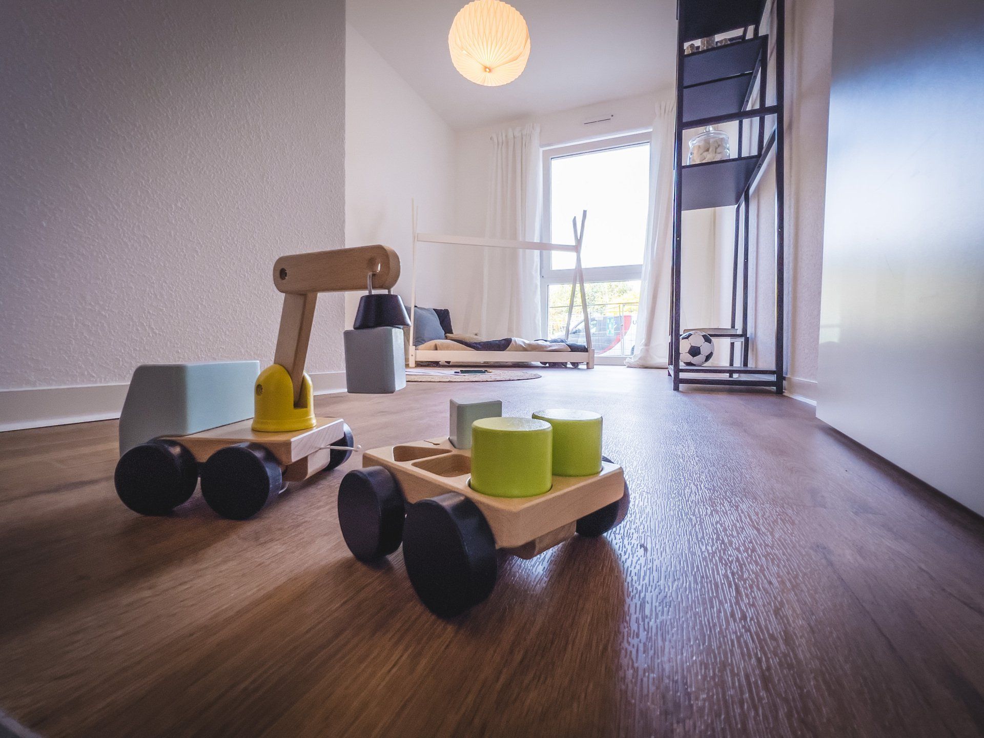 Ein Spielzeuglastwagen aus Holz steht auf einem Holzboden in einem Zimmer.