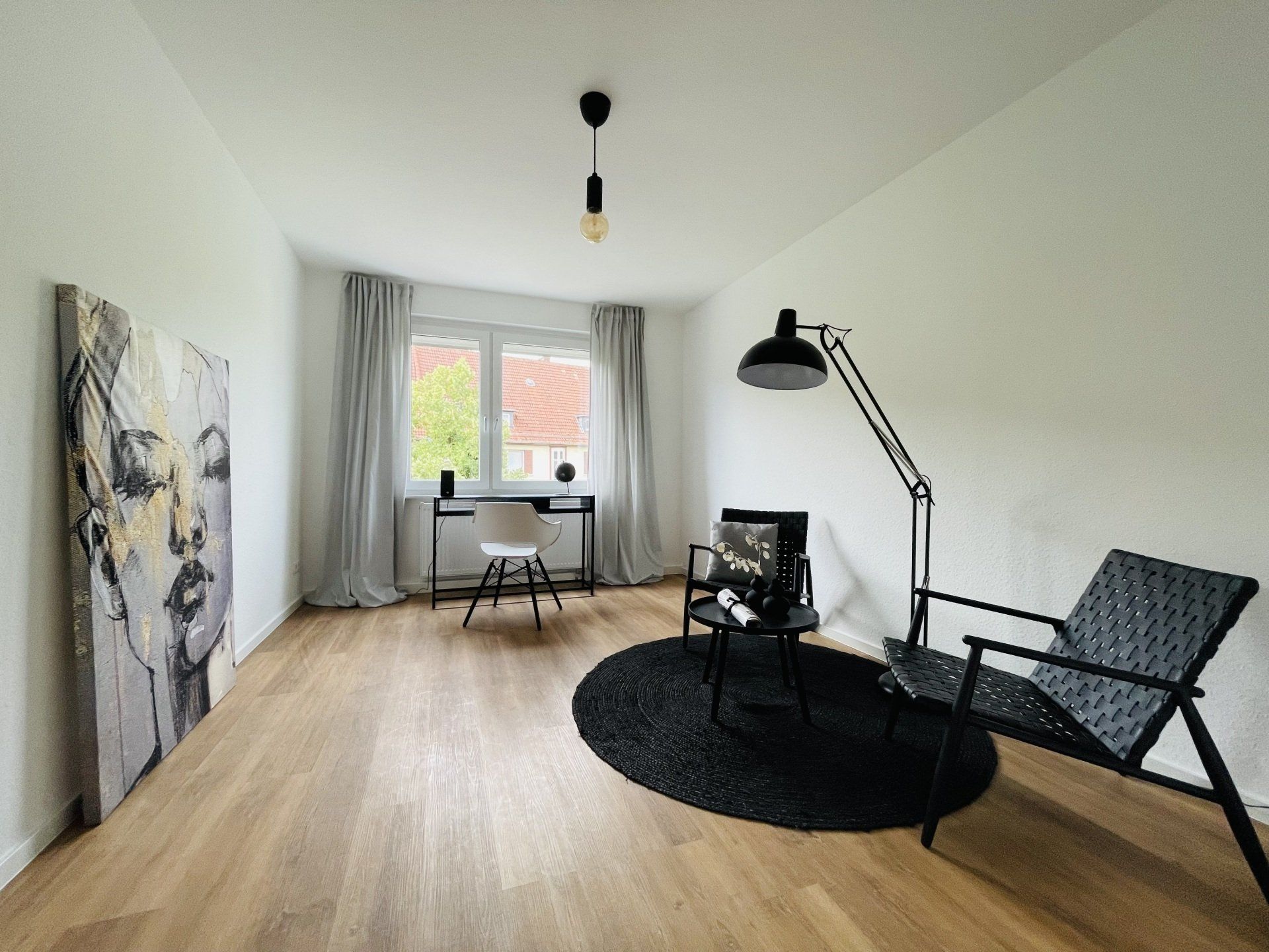 Ein Wohnzimmer mit Hartholzböden, einem Stuhl, einem Schreibtisch und einem Gemälde an der Wand.