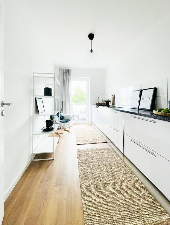 Eine Küche mit weißen Schränken und einem Teppich auf dem Boden