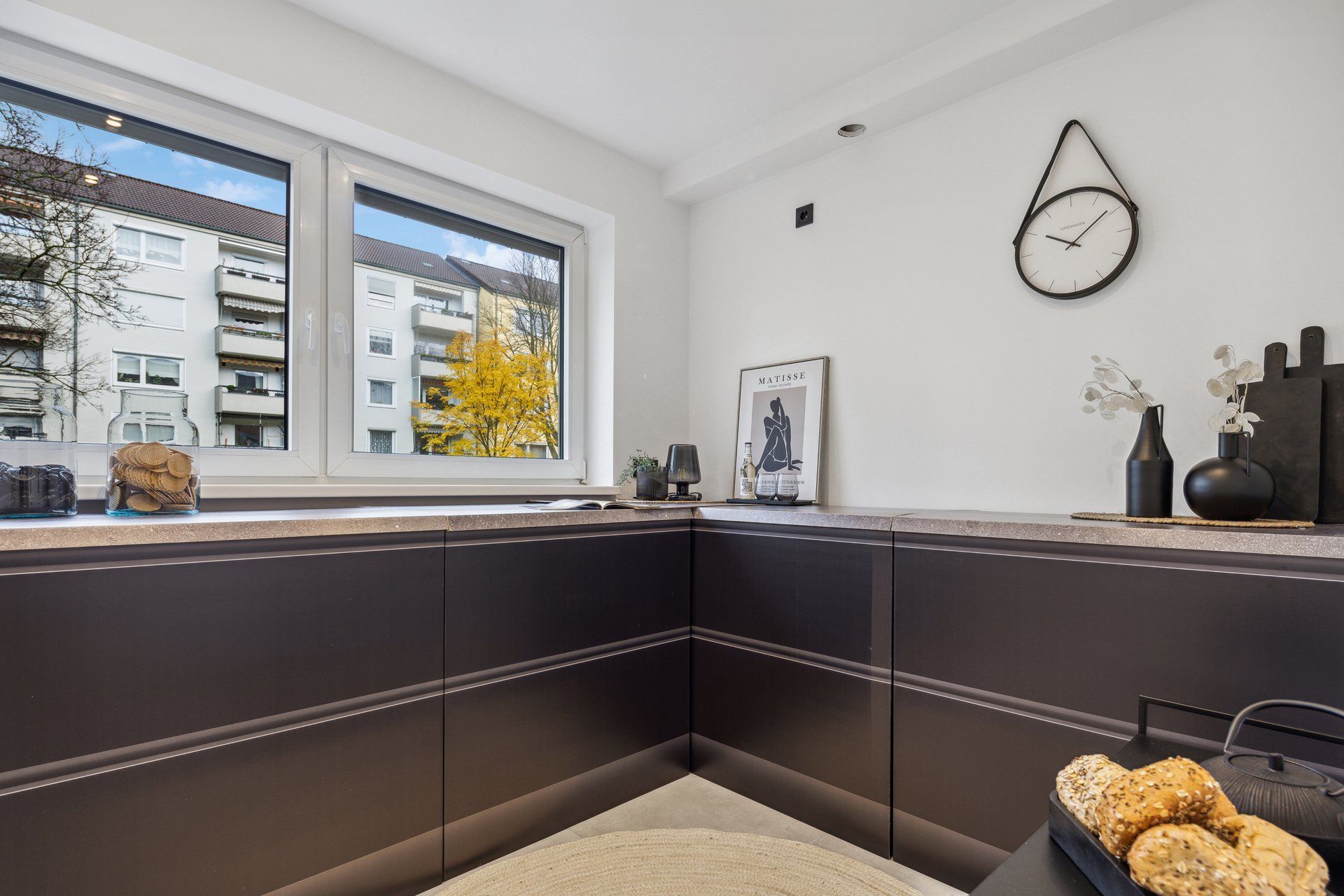 Eine Küche mit schwarzen Schränken und einer Uhr an der Wand.