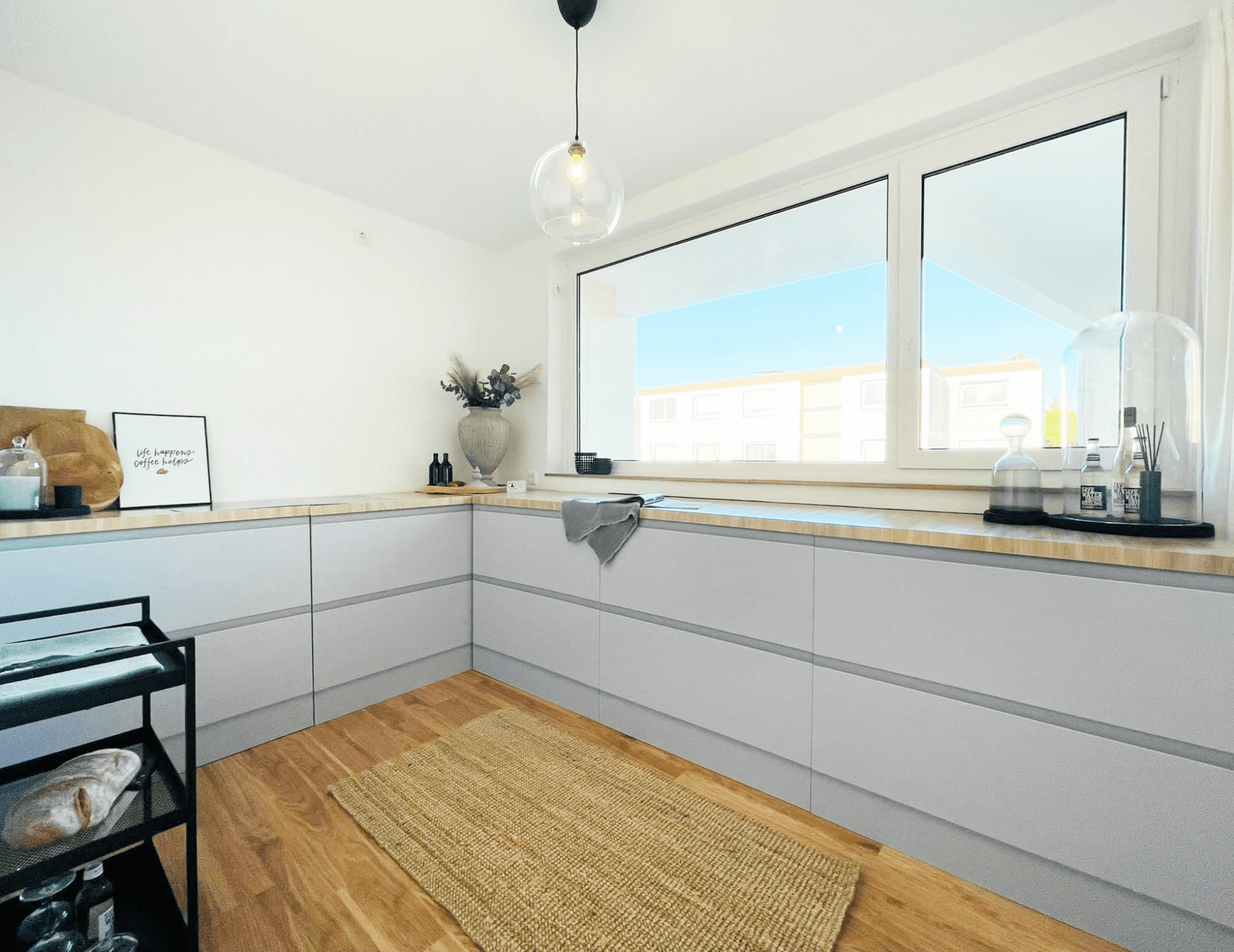 Eine Küche mit weißen Schränken und einem großen Fenster