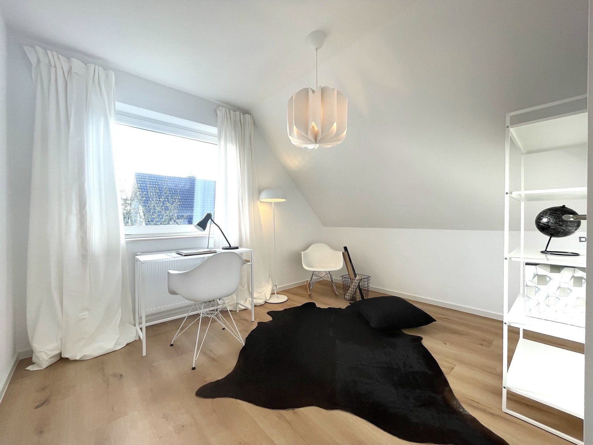 Auf dem Boden im Zimmer liegt ein schwarzer Teppich.