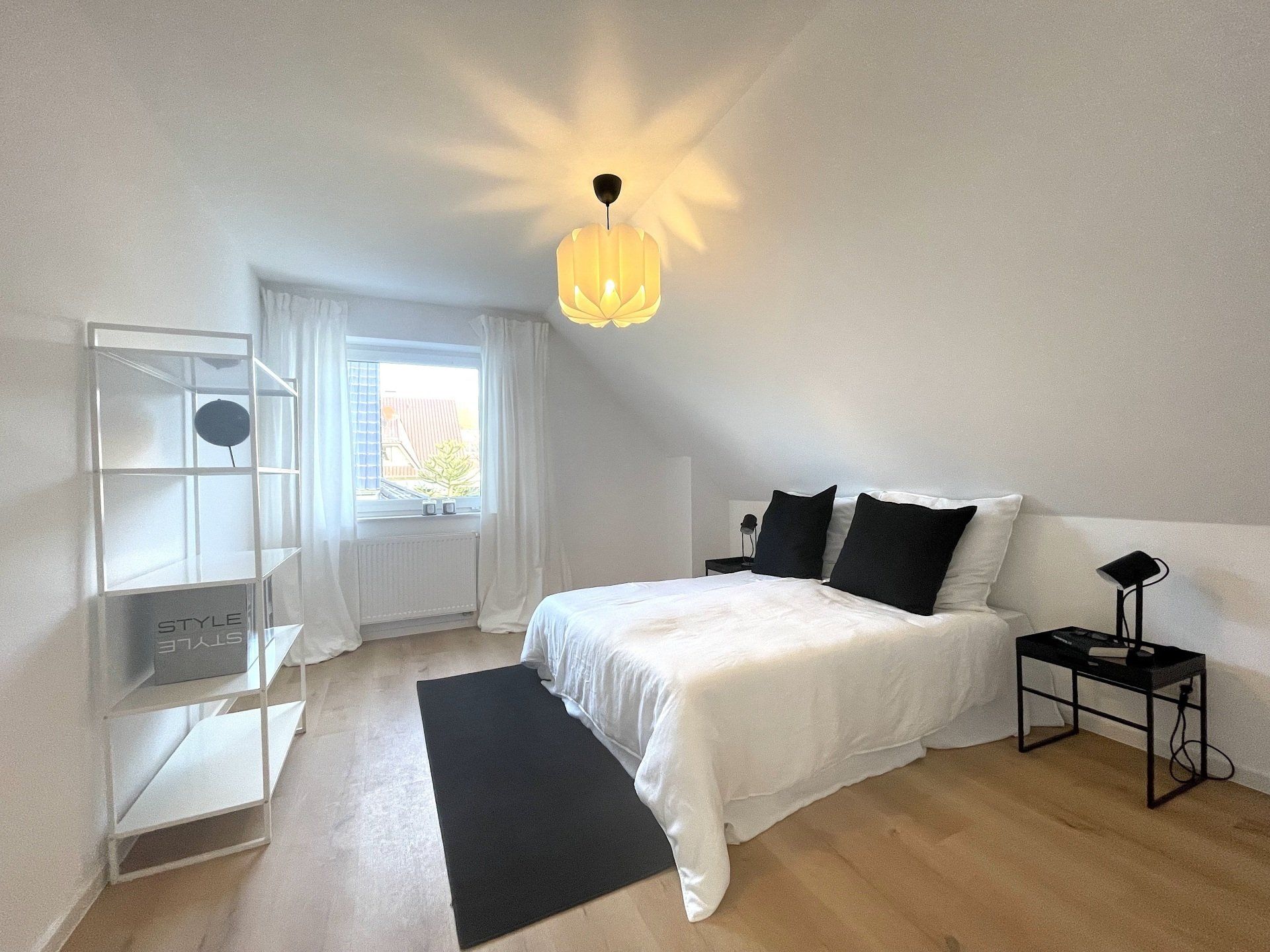 Ein Schlafzimmer mit einem Bett, einem Nachttisch und einem Fenster.