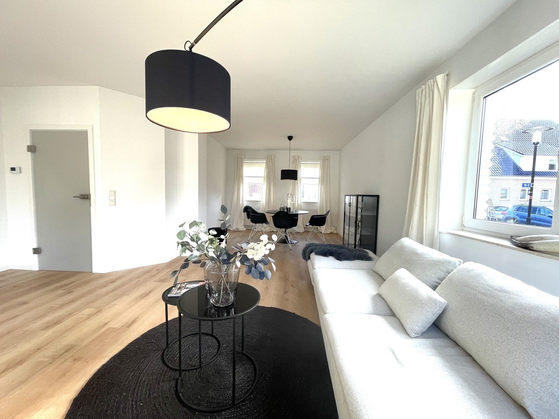 Ein Wohnzimmer mit einer weißen Couch und schwarzen Tischen