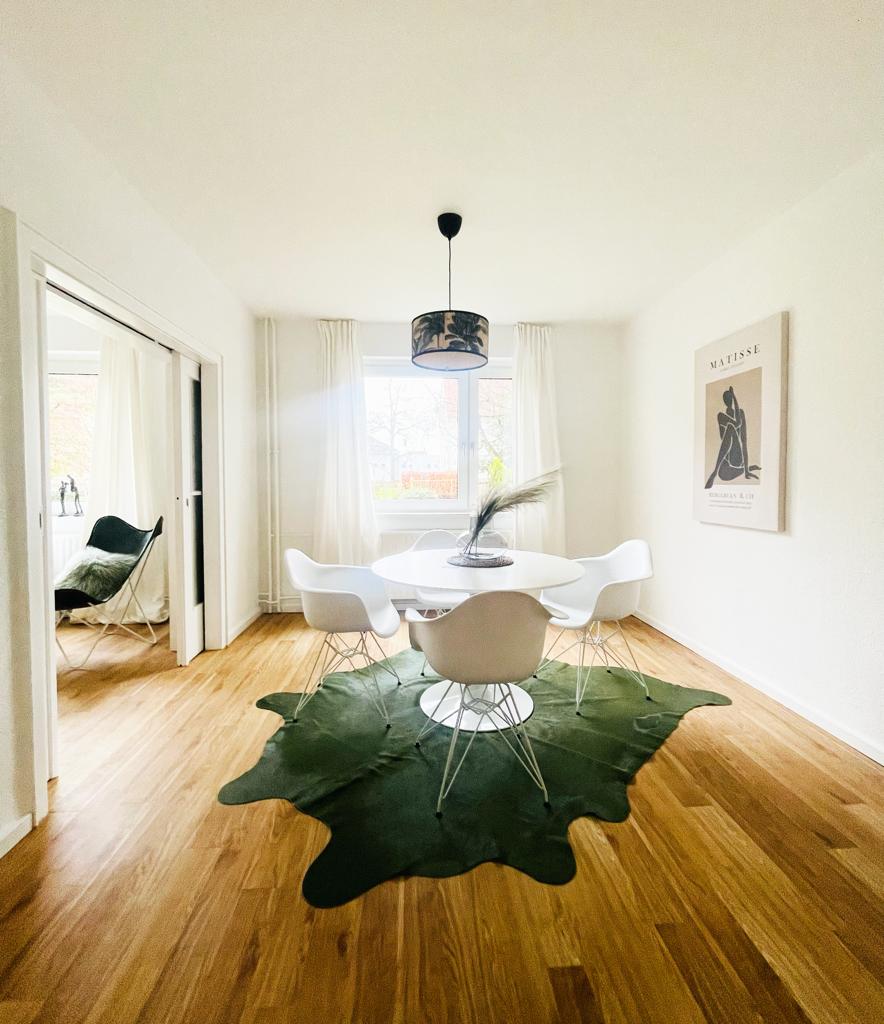 Ein Esszimmer mit Tisch und Stühlen und einem Kuhfellteppich auf dem Boden.