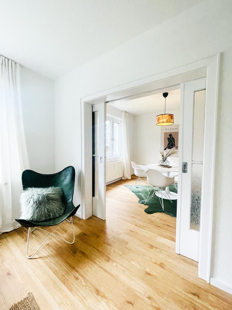 Ein Wohnzimmer mit einem Stuhl und ein Esszimmer im Hintergrund.