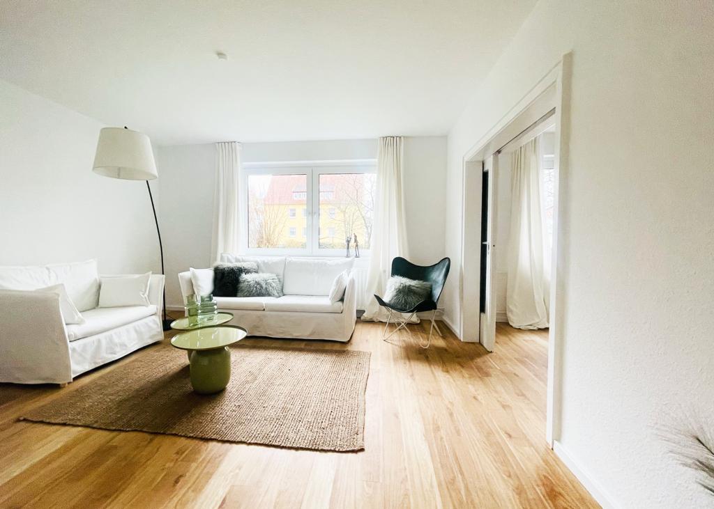 Ein Wohnzimmer mit Sofa, Sessel, Tisch und Teppich.