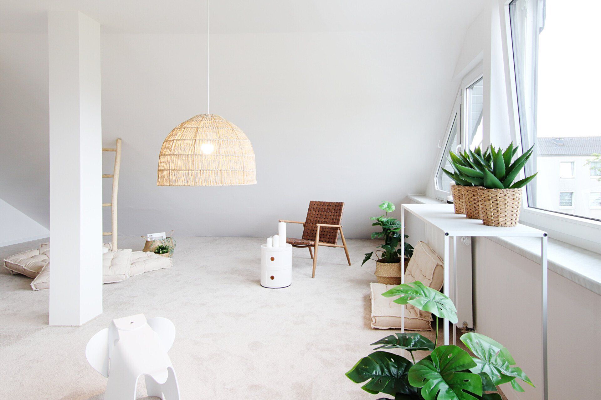 Ein Wohnzimmer mit Sofa, Sessel, Tisch und Pflanzen.