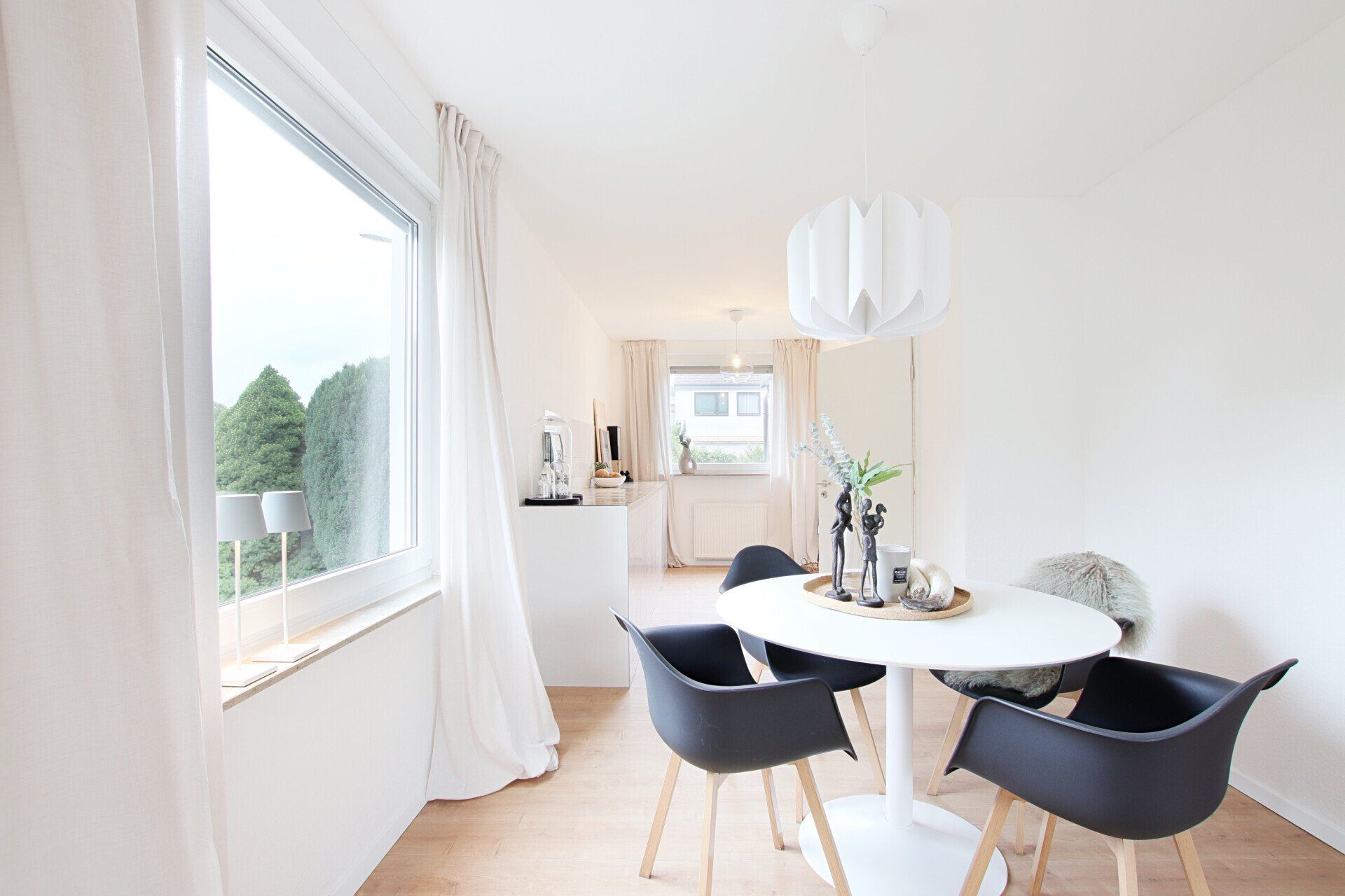 Ein Esszimmer mit einem Tisch und Stühlen vor einem Fenster.