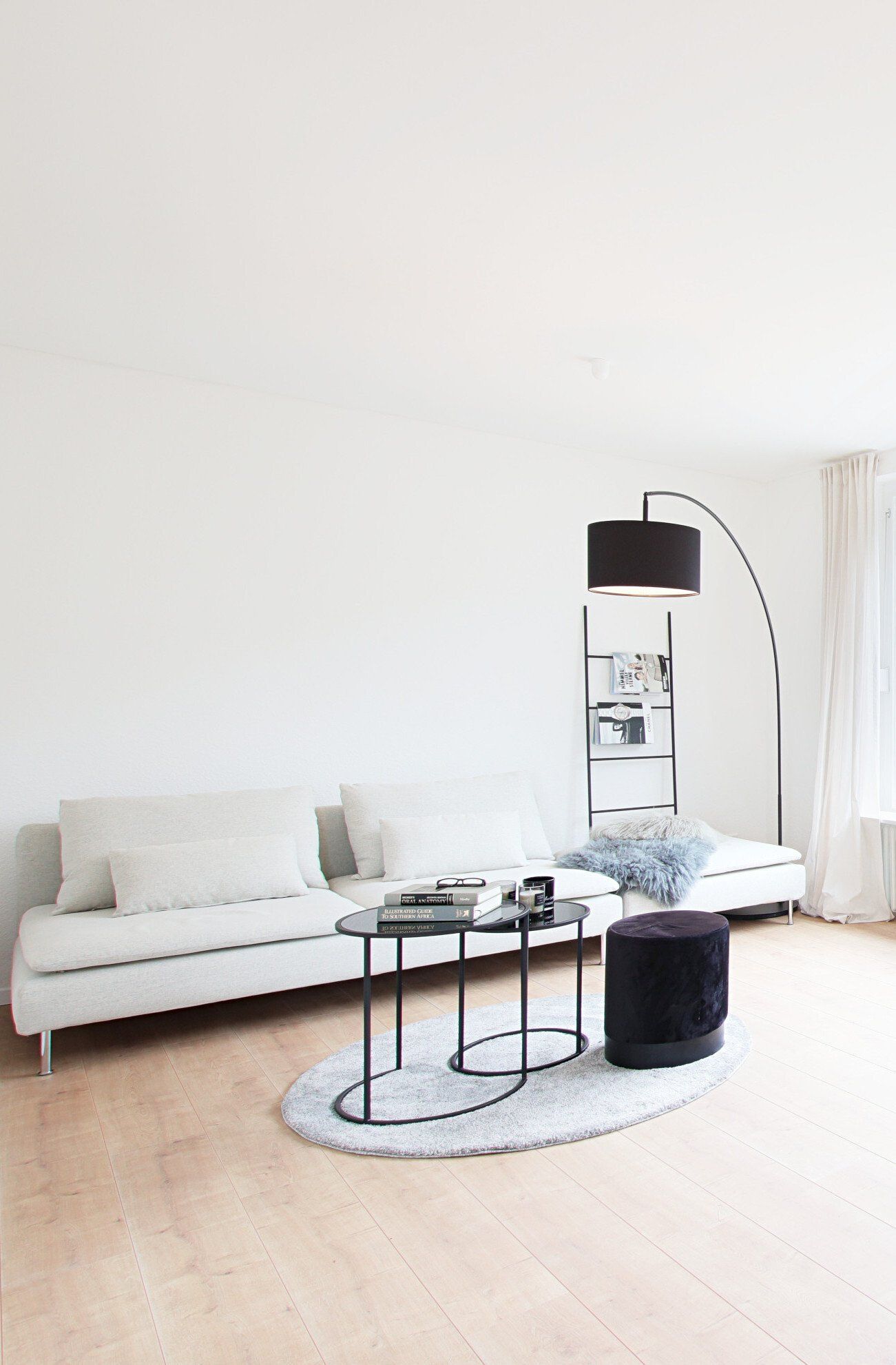 Ein Wohnzimmer mit einem weißen Sofa, zwei Couchtischen und einer Lampe.