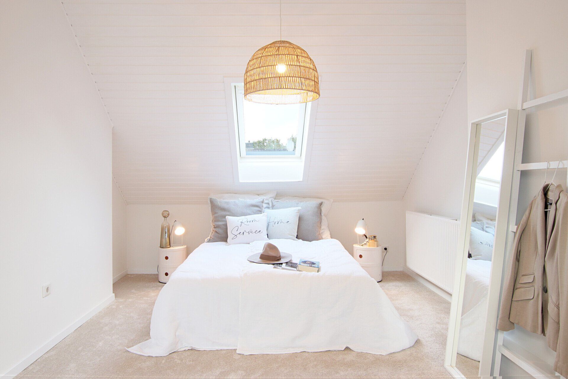 Ein Schlafzimmer mit einem Bett, Nachttischen, einem Spiegel und einem Fenster.