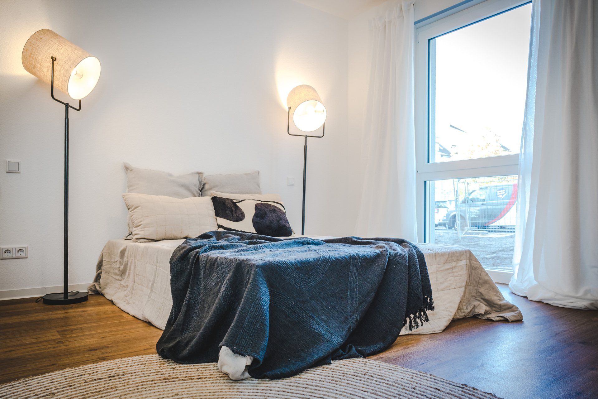 Ein Schlafzimmer mit einem Bett, zwei Lampen und einem Fenster.