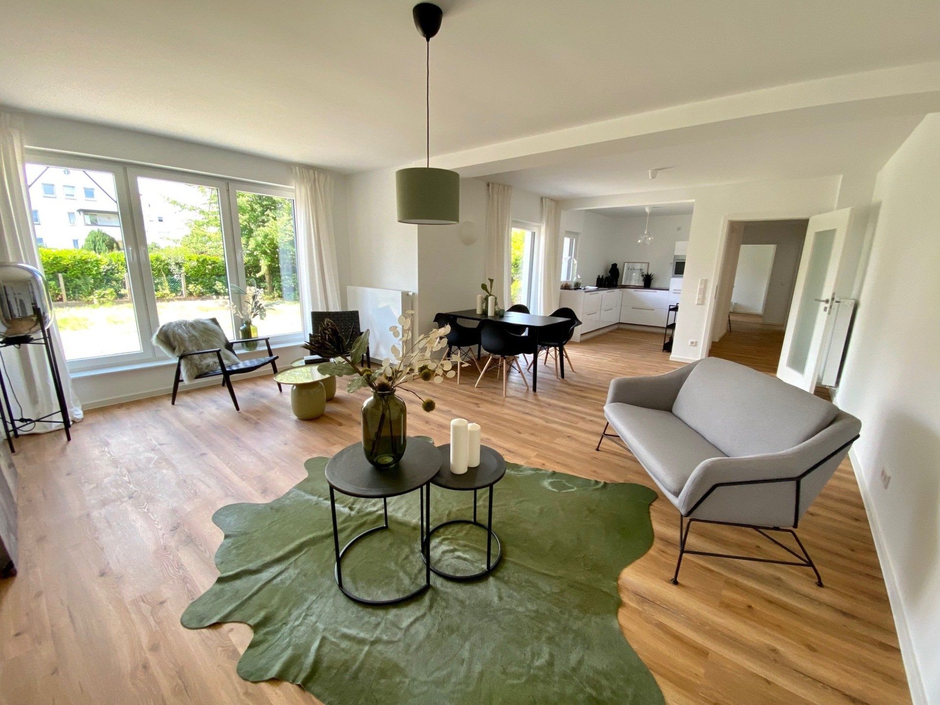 Ein Wohnzimmer mit Sofa, Stühlen, Tischen und einem grünen Teppich.