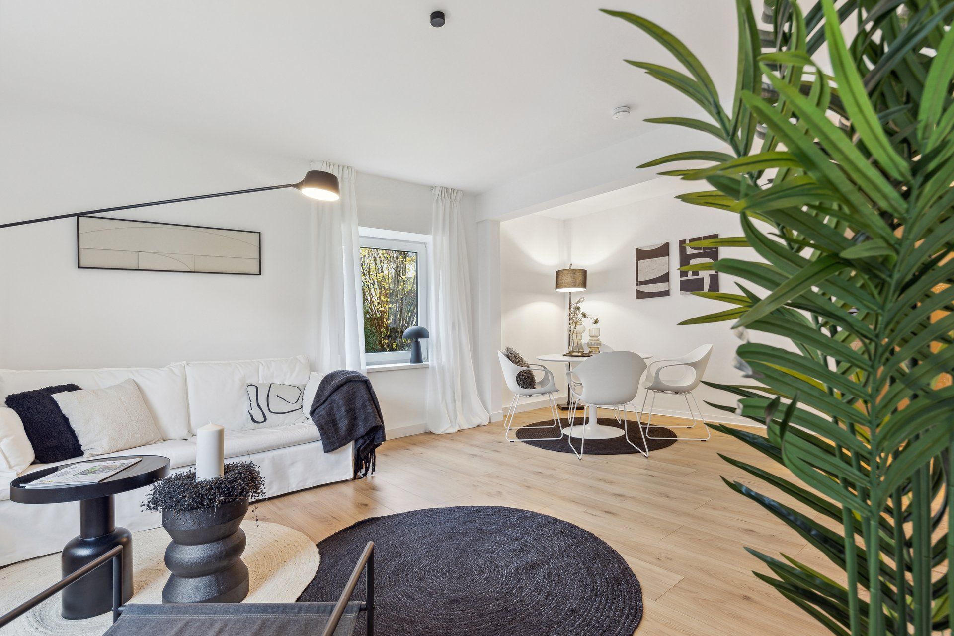 Ein Wohnzimmer mit Sofa, Tisch, Stühlen und einer Pflanze.