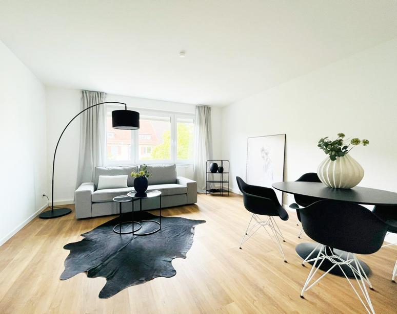 Ein Wohnzimmer mit Couch, Tisch, Stühlen und einem Kuhfellteppich.