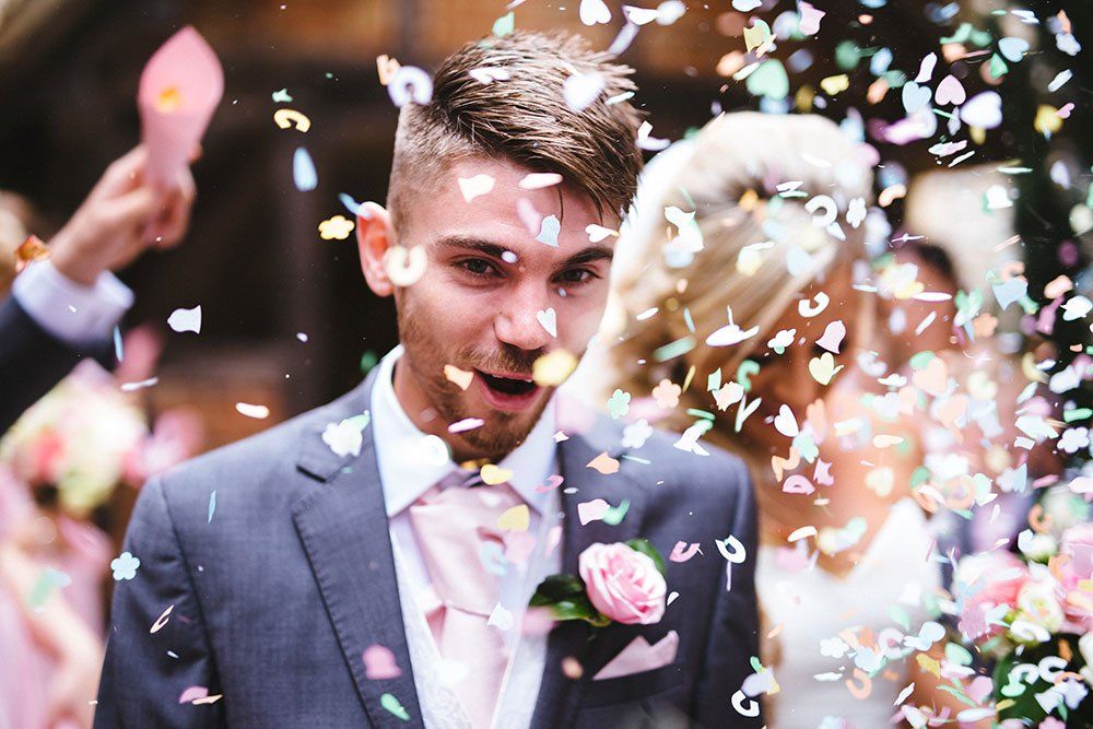 A bride and groom are being showered with confetti at their wedding reception.