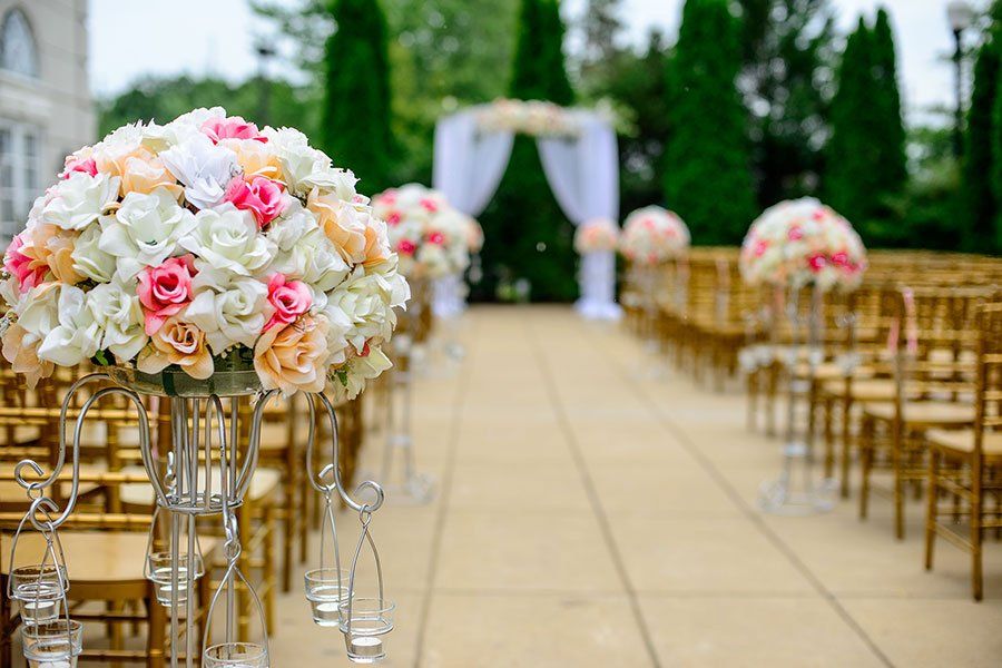 A row of chairs lined up for a wedding ceremony with flowers in vases.