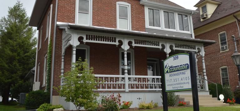 A brick house with a porch and a sign that says afternoon