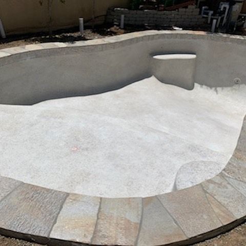 A large swimming pool is being built in a backyard.