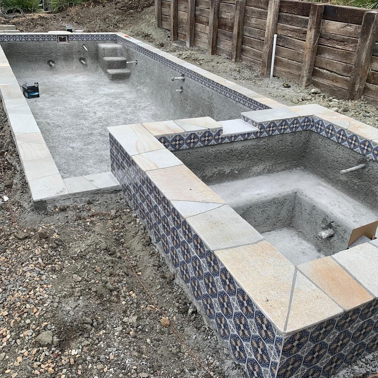 A swimming pool and a hot tub are being built in a backyard.