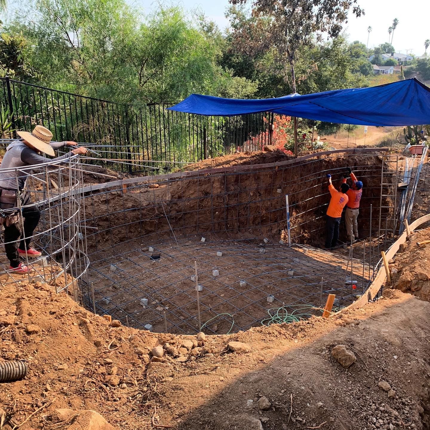 A group of construction workers are working on a large hole in the ground.