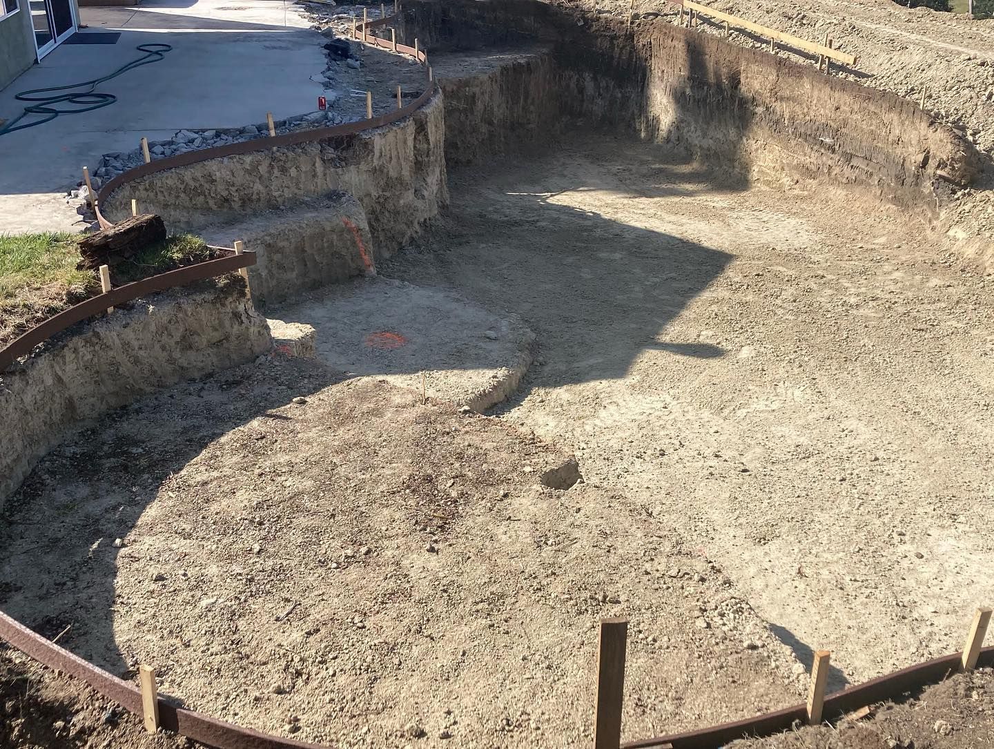 A large hole in the ground is being filled with dirt and concrete.