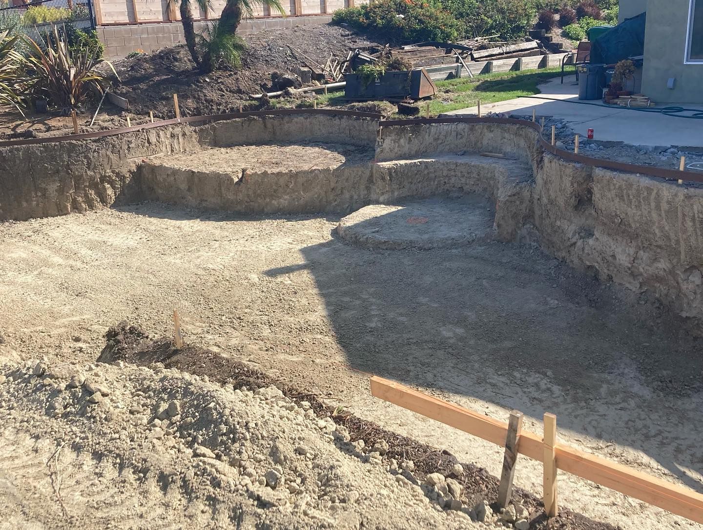A swimming pool is being built in the backyard of a house.