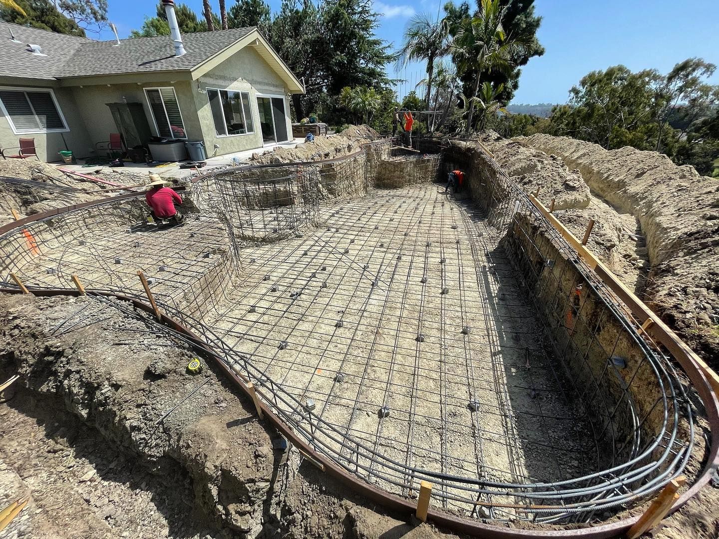 A swimming pool is being built in the backyard of a house.