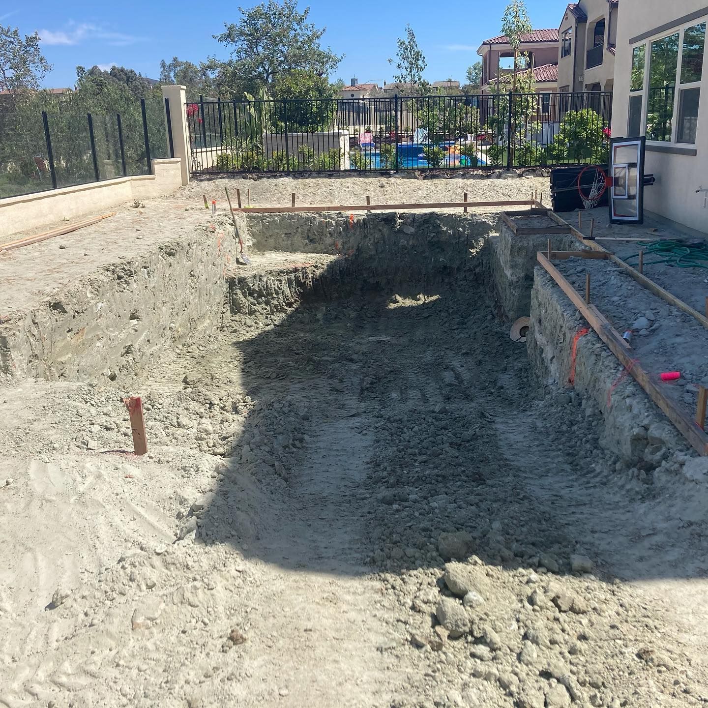 A large hole in the ground with a pool in the background