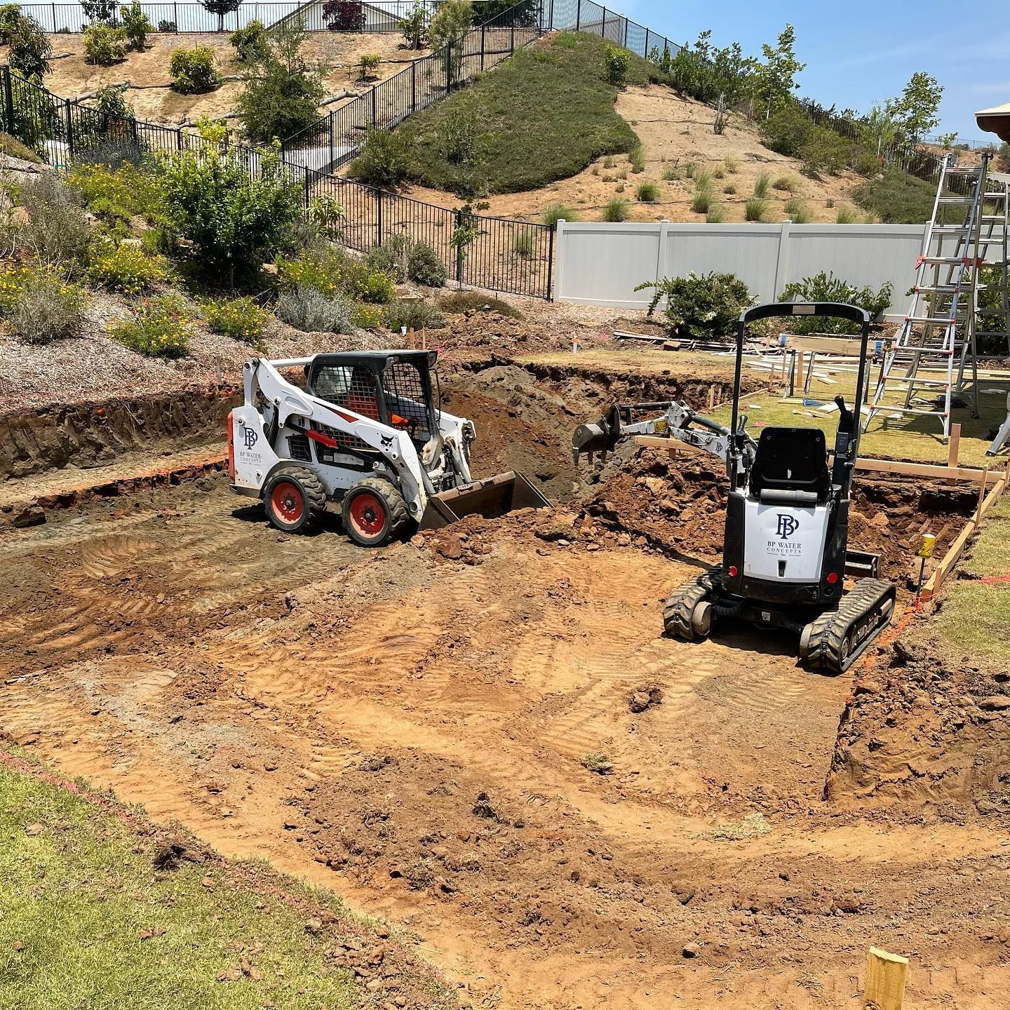 Two bulldozers are digging a hole in the dirt.