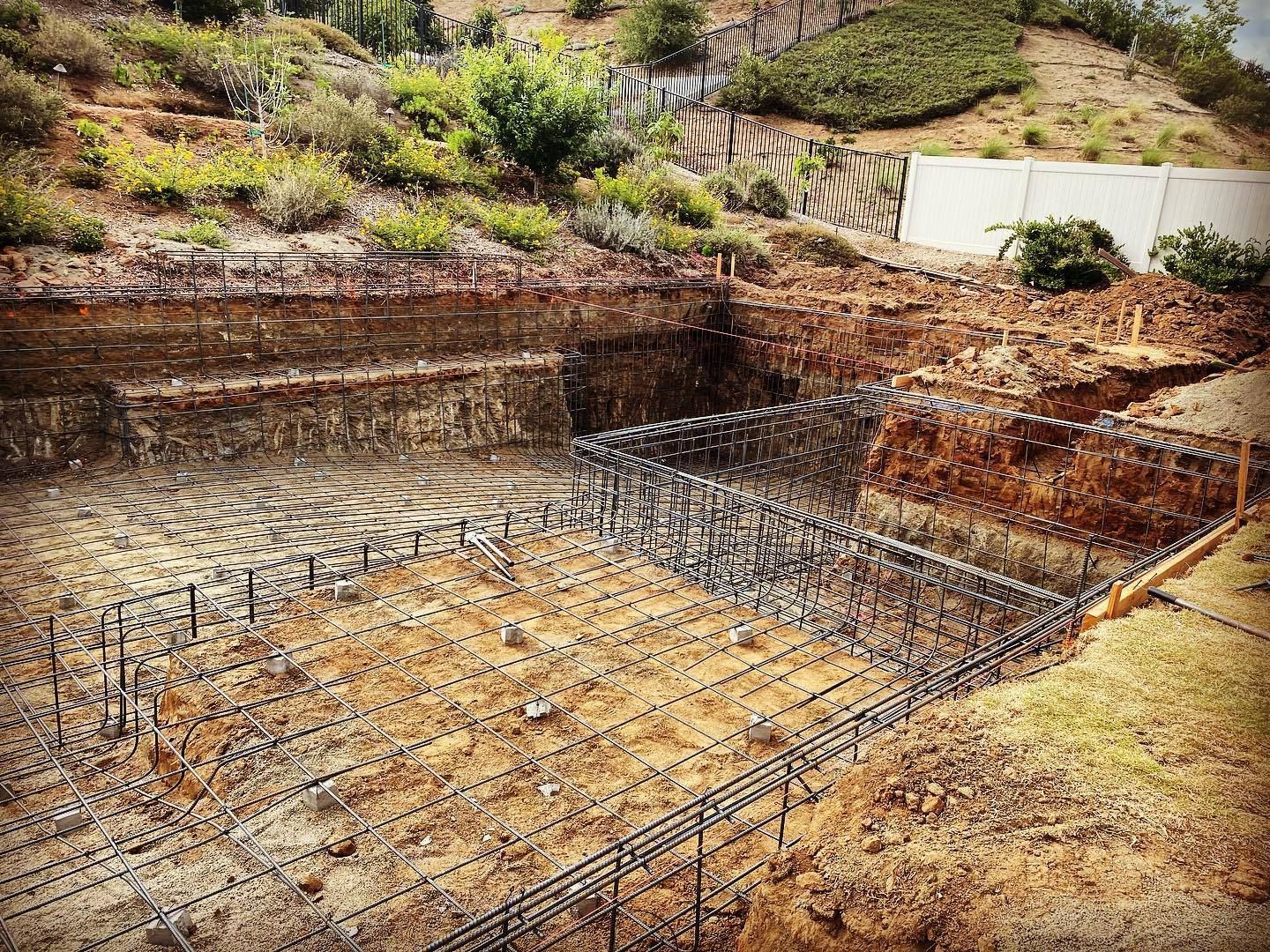 A swimming pool is being built in a dirt field.
