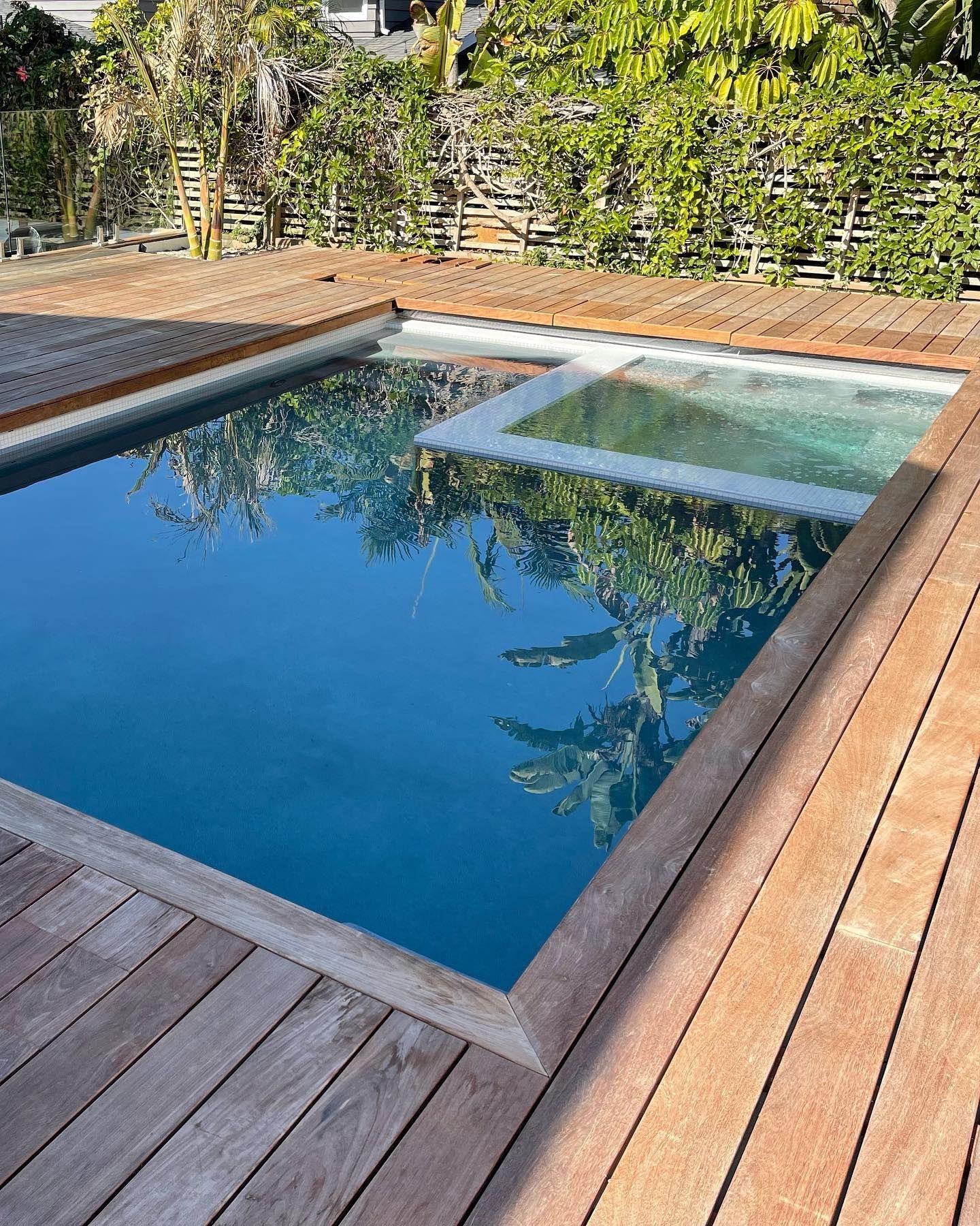 A large swimming pool is surrounded by a wooden deck.