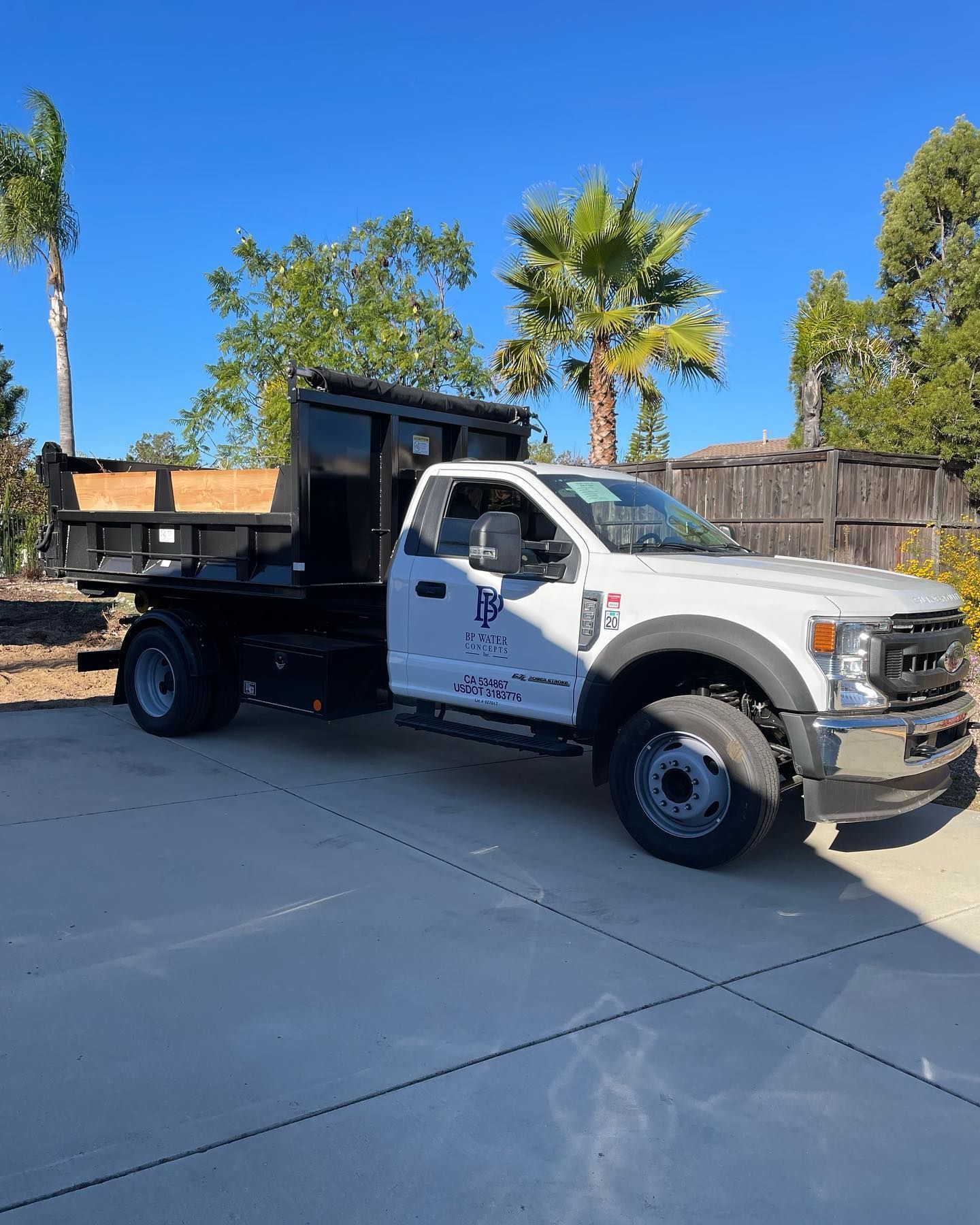 A white dump truck is parked in a driveway.
