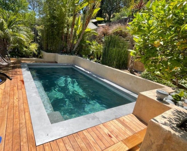 A swimming pool surrounded by trees and a wooden deck