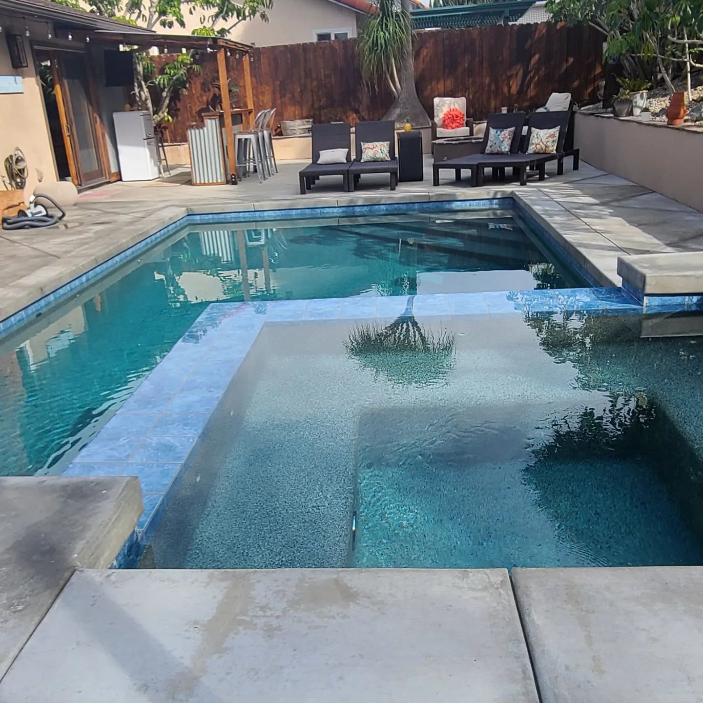 A large swimming pool surrounded by chairs and a fence
