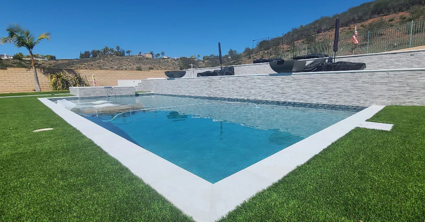 A large swimming pool in the middle of a lush green field.