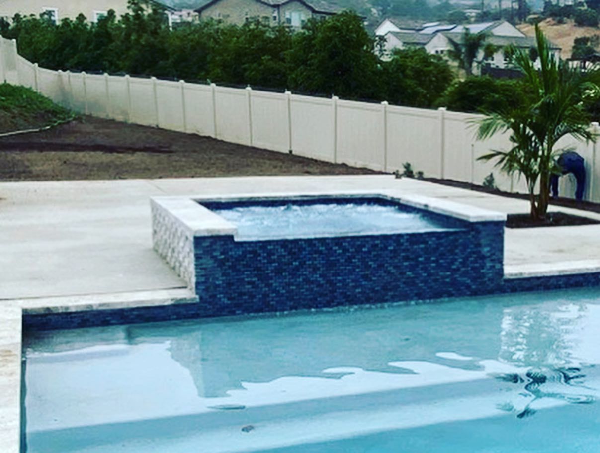 A swimming pool with a hot tub in the middle of it