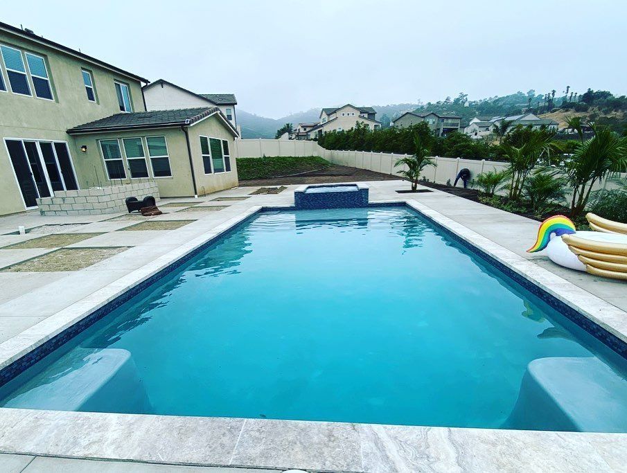 There is a large swimming pool in the backyard of a house.