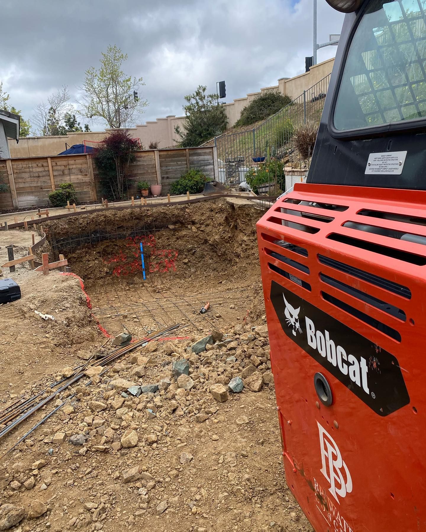 A bobcat construction vehicle is parked in a dirt field.