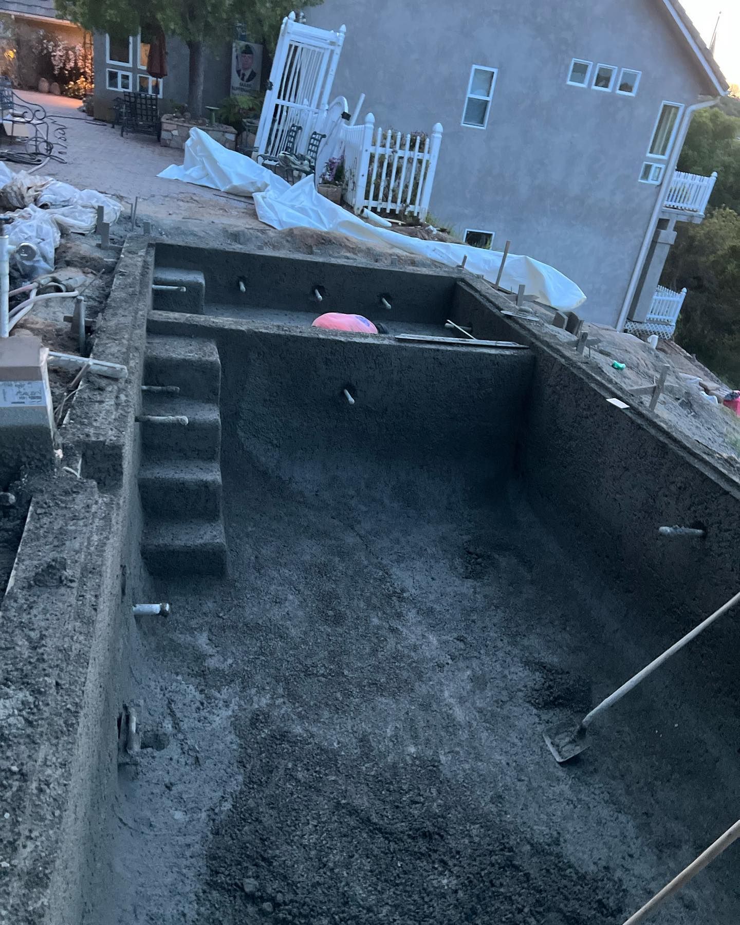 A swimming pool is being built in the backyard of a house.