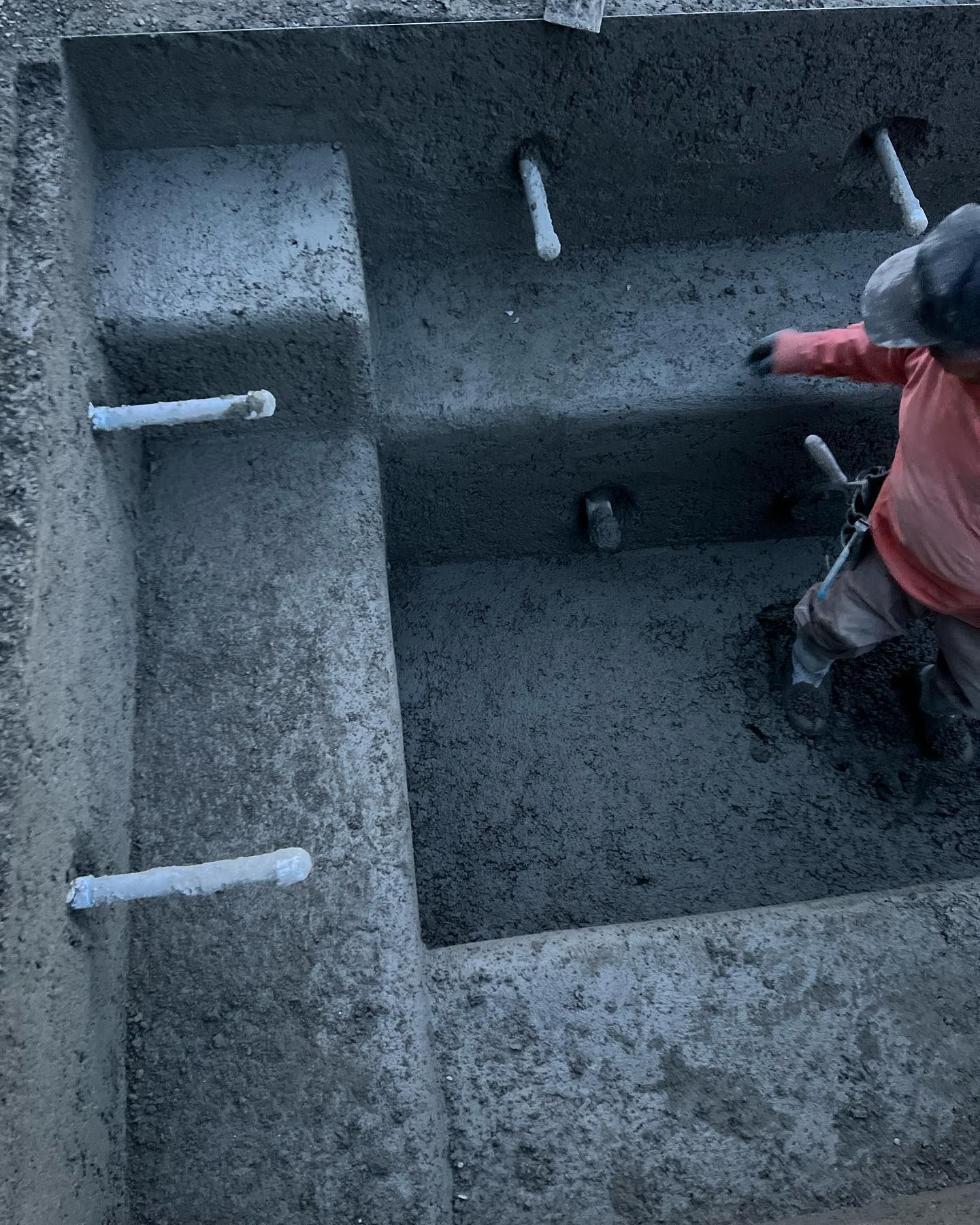 A person is pouring concrete into a hole in the ground.
