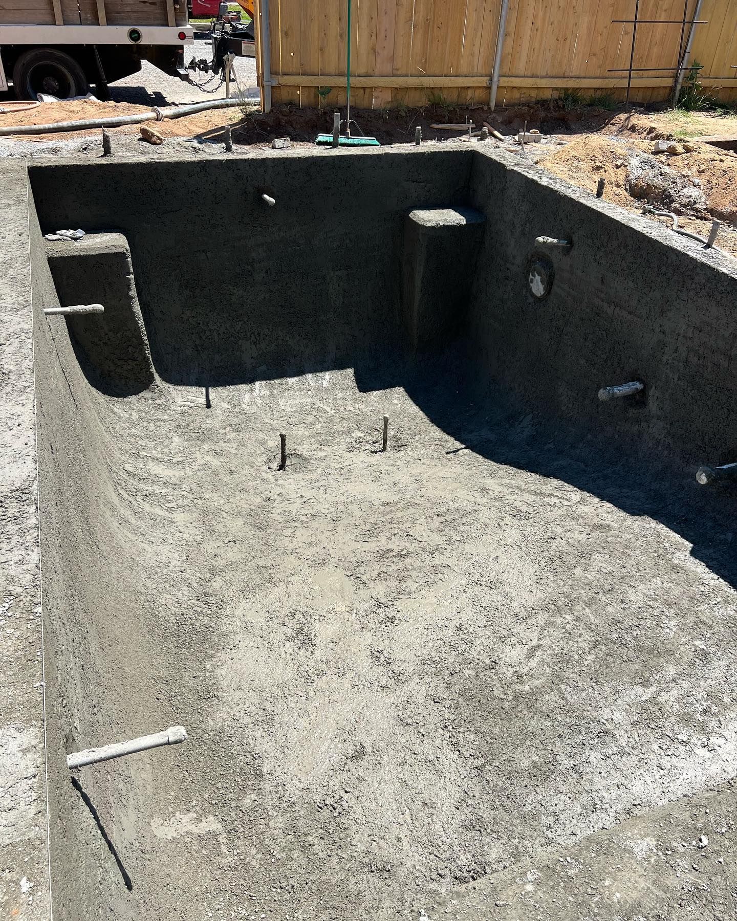 A large concrete pool is being built in a backyard.