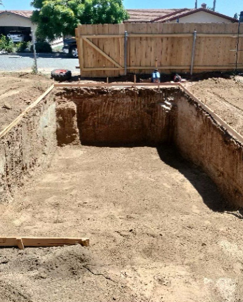 A large hole in the ground with a wooden fence in the background