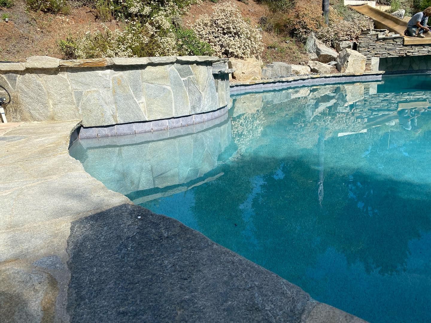 A large swimming pool with a stone wall surrounding it