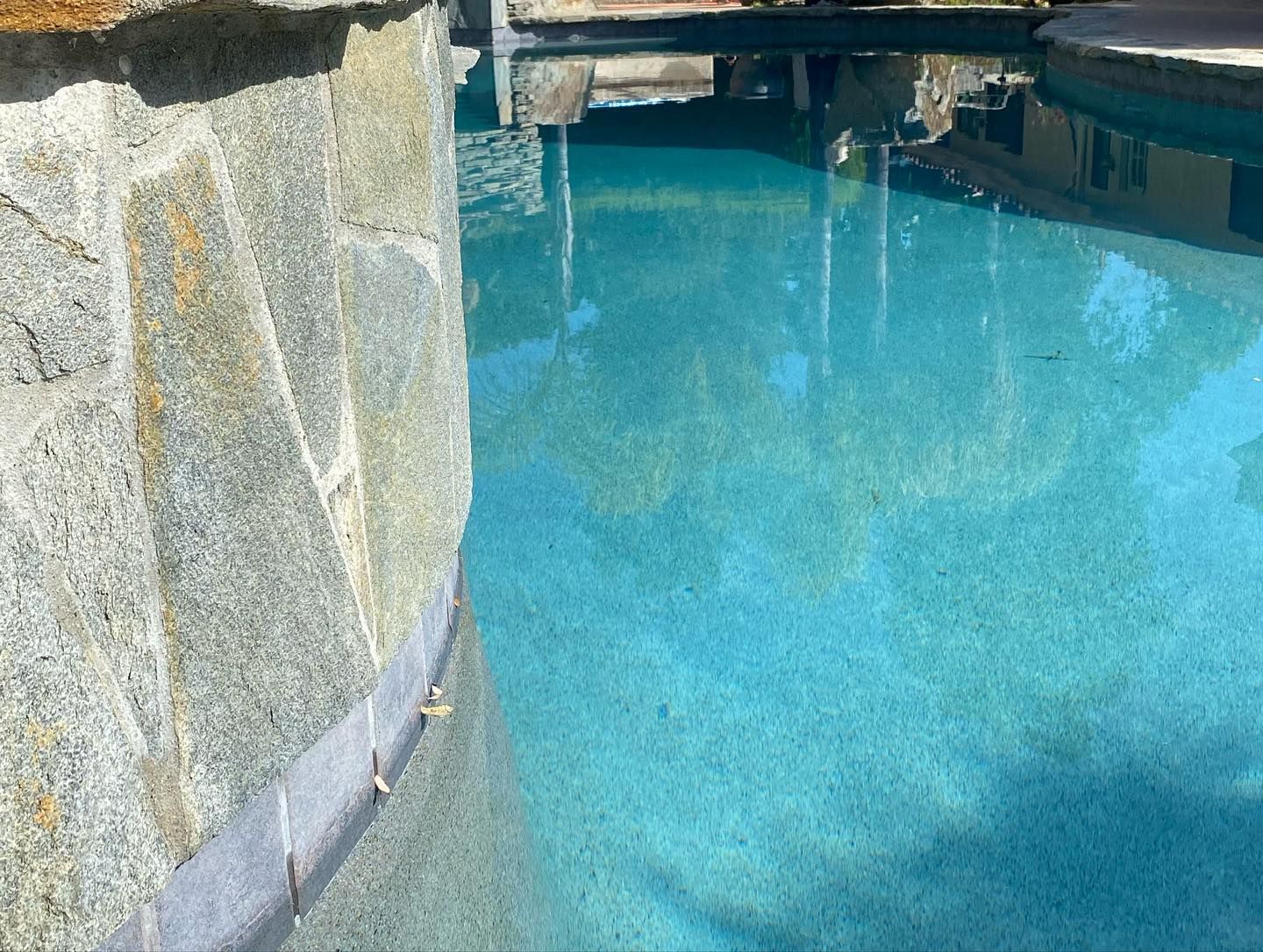 A swimming pool with a stone wall surrounding it