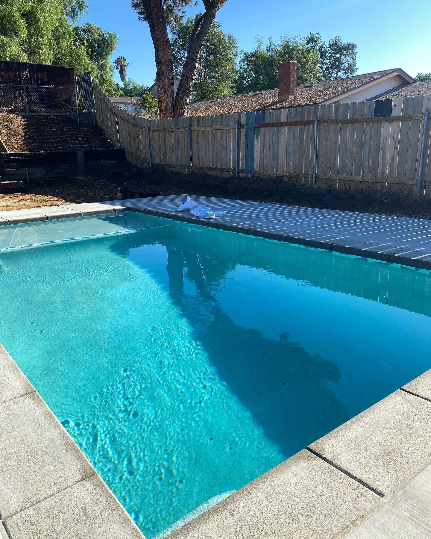 A large swimming pool with a wooden fence in the background