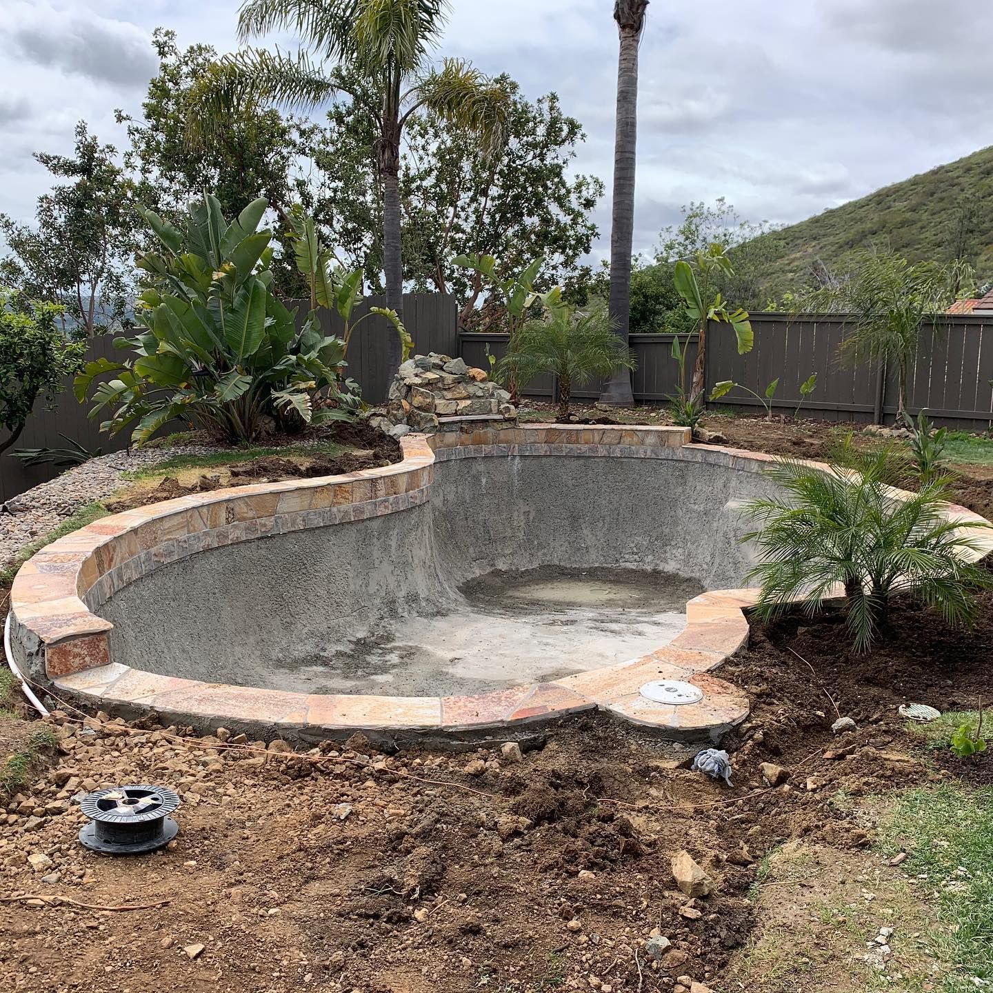 A large swimming pool is being built in a backyard.
