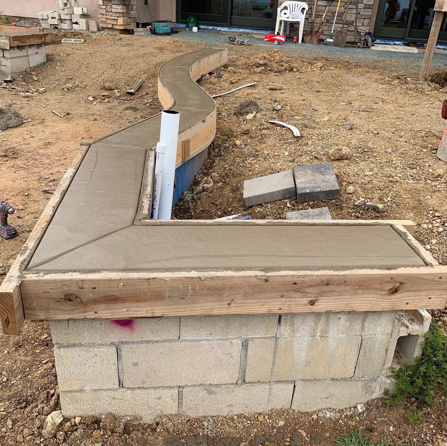 A concrete walkway is being built on top of a brick wall.