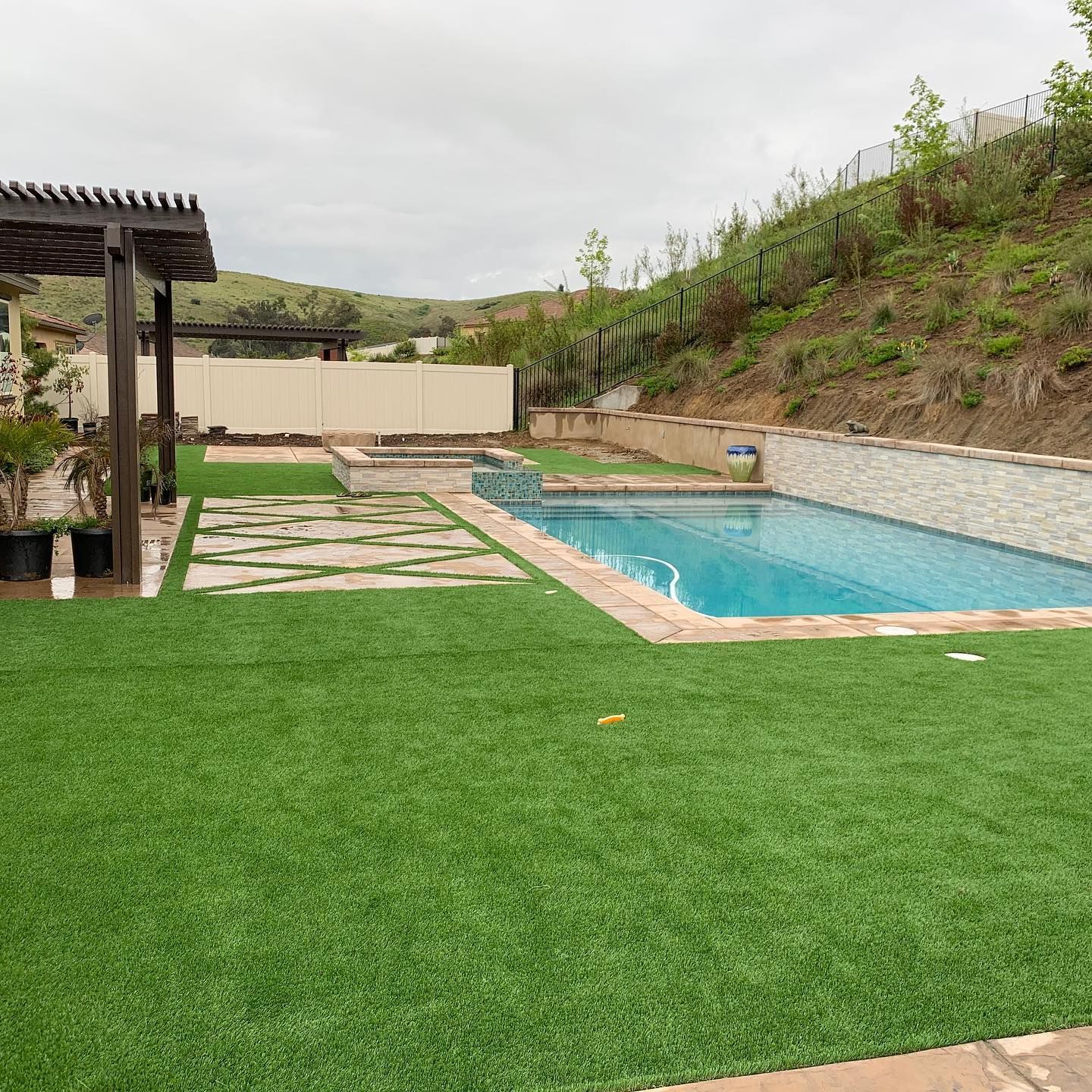 There is a large swimming pool in the backyard with a pergola.